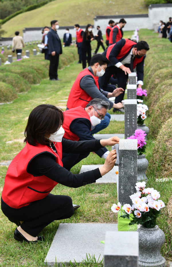 국민의힘 초선 의원들이 10일 오전 광주 북구 운정동 국립5·18민주묘지를 참배 한 뒤 열사들이 잠들어 있는 묘지의 묘비를 닦고 있다.    						             /뉴시스